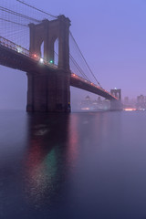 Fototapeta premium View on Brooklyn Bridge from east river on a foggy night with long exposure