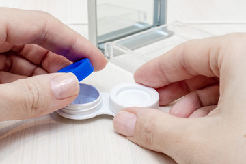 Cropped female hands taking contact lenses out of a container