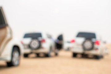 Fototapeta na wymiar SUVs travel through desert dunes, image out of focus