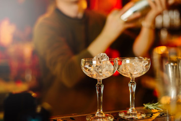 Glasses with ice. The barman is preparing strong alcoholic beverages.