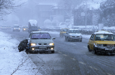 A man is repairing his car in snowy day.