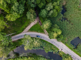 Aerial Photo of Car Driving on the Road going by the River under the Trees, Top Down View in Early Spring on Sunny Day
