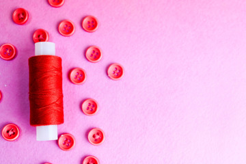 Beautiful texture with many round pink buttons for sewing, needlework and a coil of thread. Copy space. Flat lay. Pink, purple background