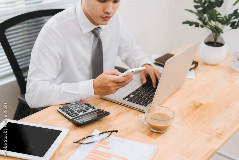 Poster business man busy working on laptop computer and using mobile smart phone in modern office, close up