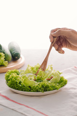 Green vegan breakfast meal in bowl with lettuce, cucumber, lime and almond. Girl holding plate with hands visible, top view. Clean eating, dieting, vegan food concept
