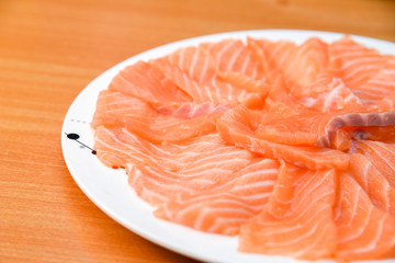 Slided Raw Salmon in white dish on wood blackground