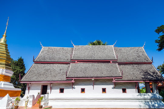 Church of Wat Phra That Benk Sakat and golden pagoda against blue sky.