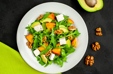 Avocado salad with baby spinach and pomegranate on a white plate on the background of slate, stone or concrete.