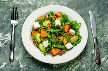 Salad of arugula, cheese, beet, walnut, on the background of slate, stone or concrete.