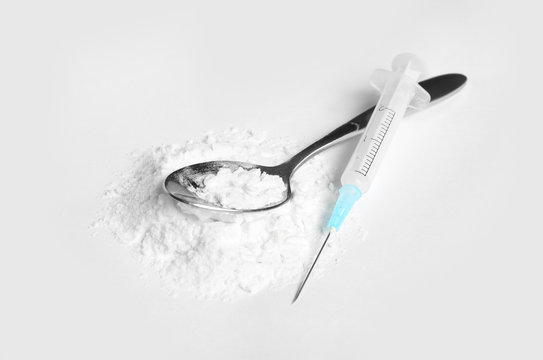 Spoon with cocaine and empty syringe on white background