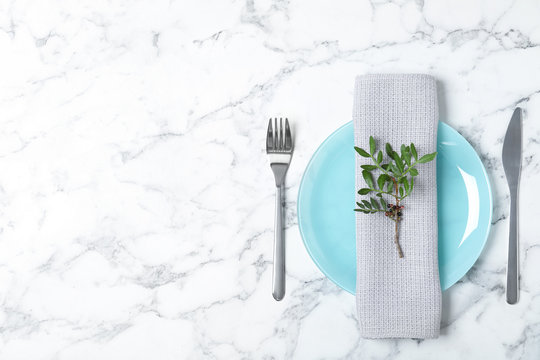 Beautiful table setting with napkin on marble background, top view. Space for text