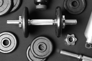 Flat lay composition with dumbbell and parts on dark background