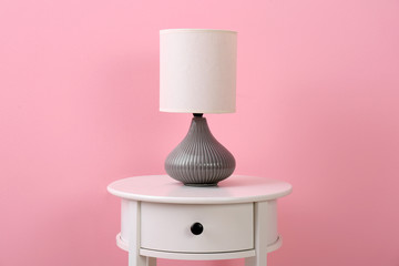 Stylish lamp on table against color background