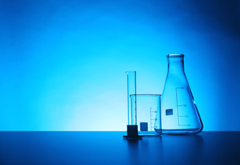 Empty chemistry laboratory glassware on table against color background