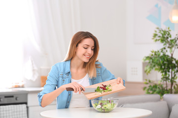 Obraz na płótnie Canvas Happy young woman preparing salad in kitchen. Healthy diet