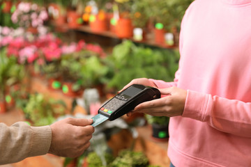 Client using credit card for terminal payment in floral shop, closeup