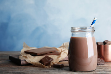Jar with tasty chocolate milk on wooden table, space for text. Dairy drink