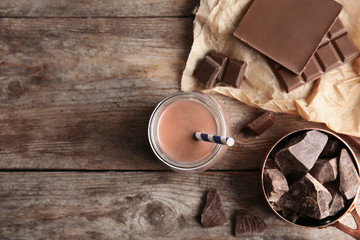 Flat lay composition with jar of tasty chocolate milk and space for text on wooden background. Dairy drink