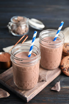 Jars with tasty chocolate milk on wooden table. Dairy drink