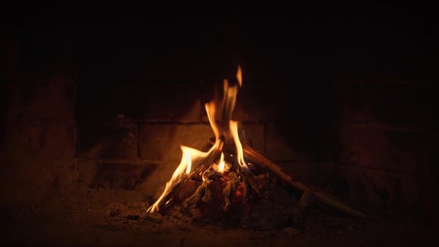 Flames dance over split logs, illuminating hearth and brick backwall