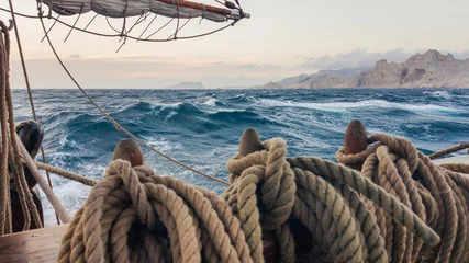 Fototapeten Altes Segelschiff, das auf dem Meer nahe den Felsen läuft. Sicherungsstift, an dem die Seile © chocolatefather