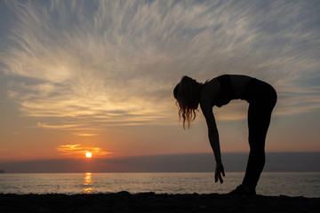 young woman does exercise at sunrise