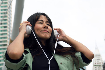 Close up beautiful woman listening music and offices building background.