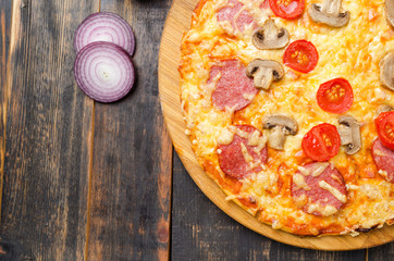 Italian pizza with tomatoes and mushrooms on a wooden board