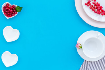 set-up table with plates, wineberry and flower on blue background top view mock-up