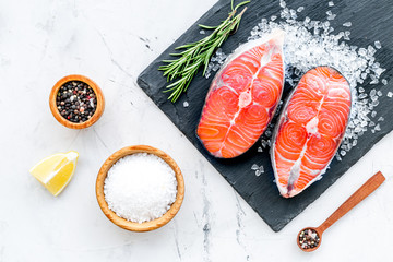 Fresh salmon steak with spices, rosemary, lemon for cooking healthy food on marble background top view