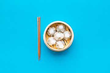 Dim sums with red pepper and vegetables with sticks in Chinese restaurant on blue background top view