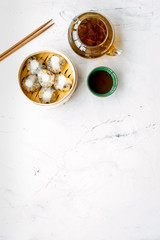 Obraz na płótnie Canvas Chinese steamed dumplings Dim Sum in bamboo steamer with tea on marble background top view mock up