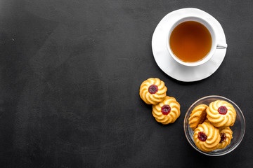 Dessert for evening tea. Cup of tea, fresh homemade cookies on black background top view space for text
