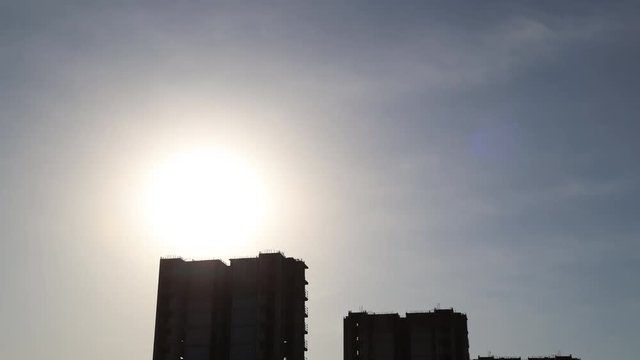 The sun sets between buildings.