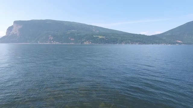 Aerial dolly passing through narrow dock posts revealing beautiful blue lake