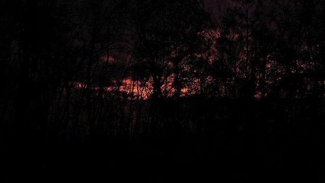 Aerial view of a spectacular sunset behind some beautiful mountains and the silhouette of some trees in the foreground.