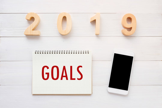 2019 goals on note paper and smart phone with blank screen on white marble background, new year aim to success in business background, banner