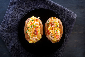 Baked potatoes with bacon and mushrooms in a rustic way on a wooden board. Close-up. Copy space. Top view
