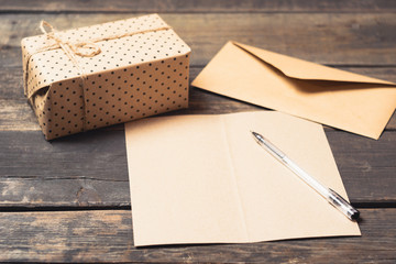  A letter and envelope from paper, a gift tied with a cord on a wooden vintage background. A sheet of blank paper for congratulations or treatment. View from above. Copy space.  Selective focus.