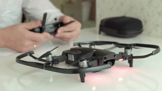 mature man in glasses and a white shirt controls quadcopter from the console, test flight, the concept of the study of technology, close-up