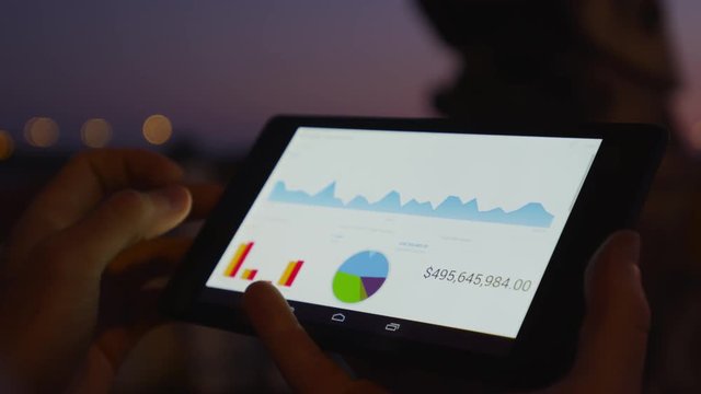Businessman working on mobile platform outdoors managing a project Application using graphic charts looking at the data pies and vectors graphics