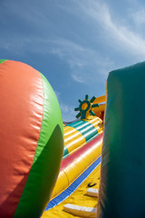 A giant colorful inflatable slider with joyful kids running up and down the slider in the fun park with happiness.