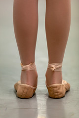 Young girl pre-pointe in ballet school class with rolled ankles - in incorrect ballet first 1st position. Portrait format with copy space. Best images for young girl ballet poster.