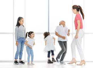 Fototapeta premium Asian woman in pink shirt teach Asian boy and girls to move their body, they stand in front of big white window.