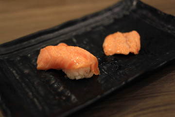 Fresh japanese salmon burn sushi on black plate.