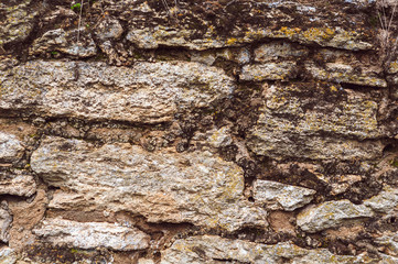 background of a wall of raw granite stone with moss