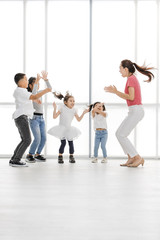 Fototapeta premium Asian woman in pink shirt playing something with Asian boy ans girls, they jump together, they stand in front of big white window.
