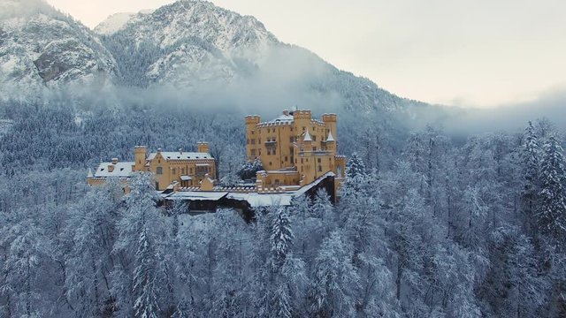 Aerial view of Hohenschwangau Castle at sunrise in winter landscape.