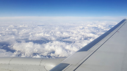 Fototapeta na wymiar flying and traveling abroad, view from airplane window on the wing on cloudy blue sky aboard morning winter time, journey backgrounds