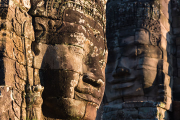 Stone faces in Bayon, Angkor Thom temple, selective focus sunset light. Buddhism meditation concept, world famous travel destination, Cambodia tourism.